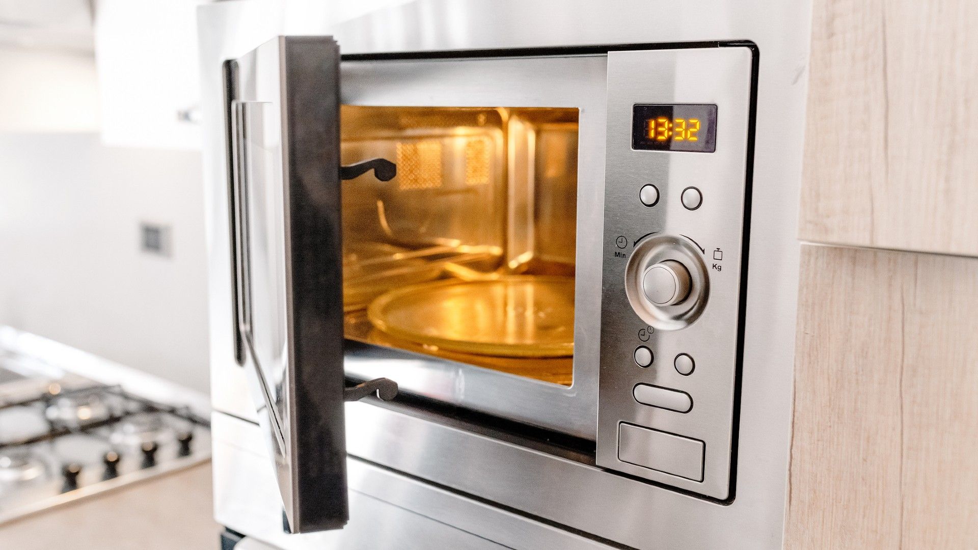 empty microwave with door open and light on, built into a kitchen