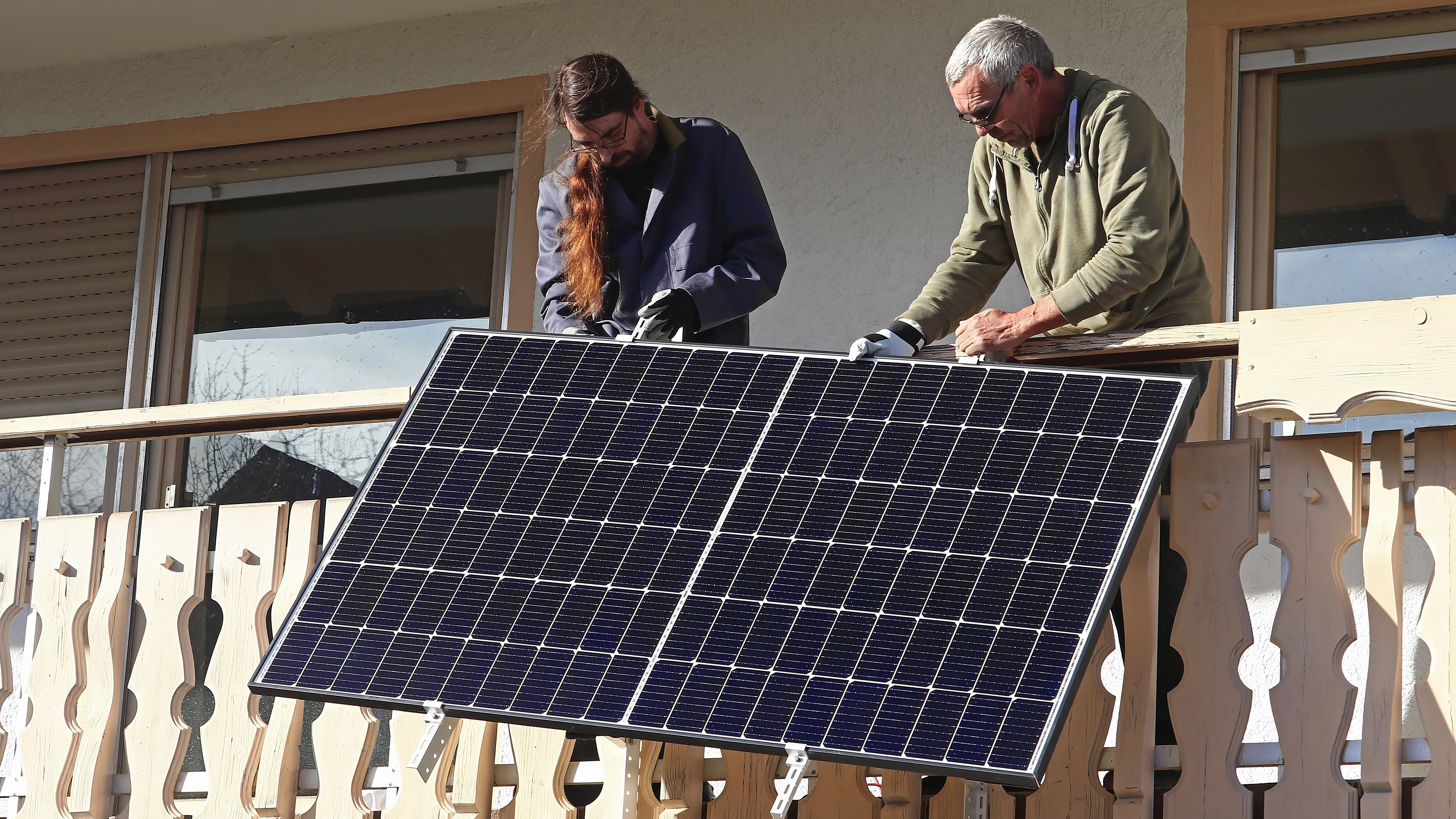 Two men installing a balcony solar panel