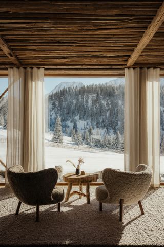 A modern rustic, organically furnished ski hotel features wooden volumes brought to life by soft shearling seating, sculptural furniture, flowing curtains, and shearling floors.