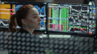 Emily (Phoebe Dynevor) in front of her computer monitors in Fair Play