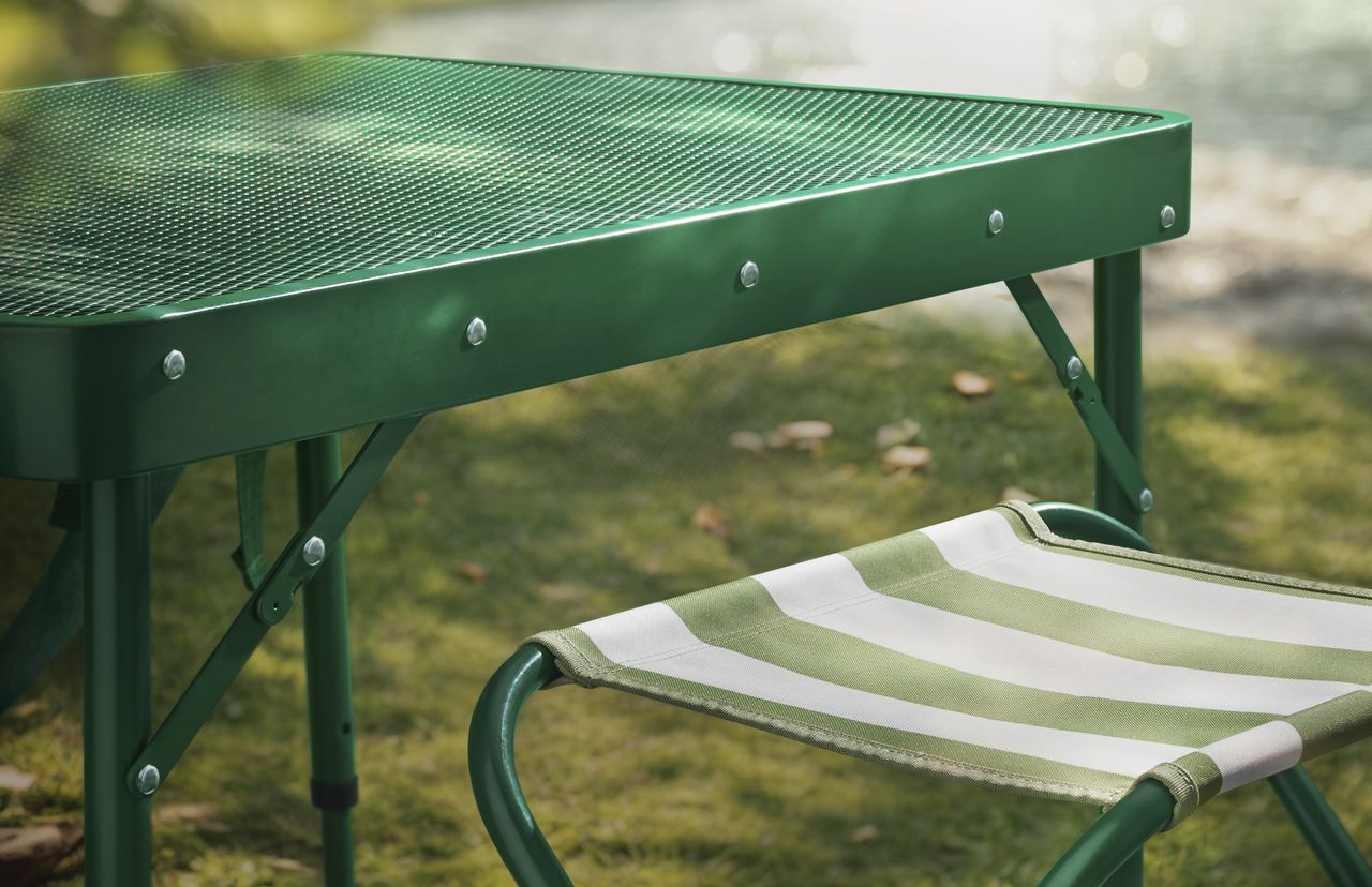 A green picnic table with striped folding chairs