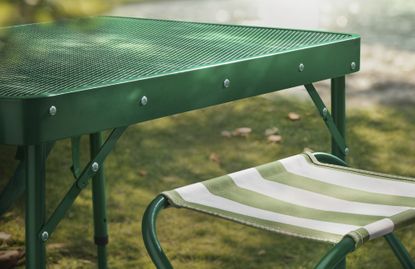 A green picnic table with striped folding chairs