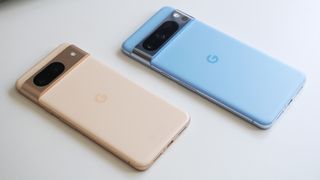 En beige Google Pixel 8 och en blå Pixel 8 Pro ligger på ett vitt bord.