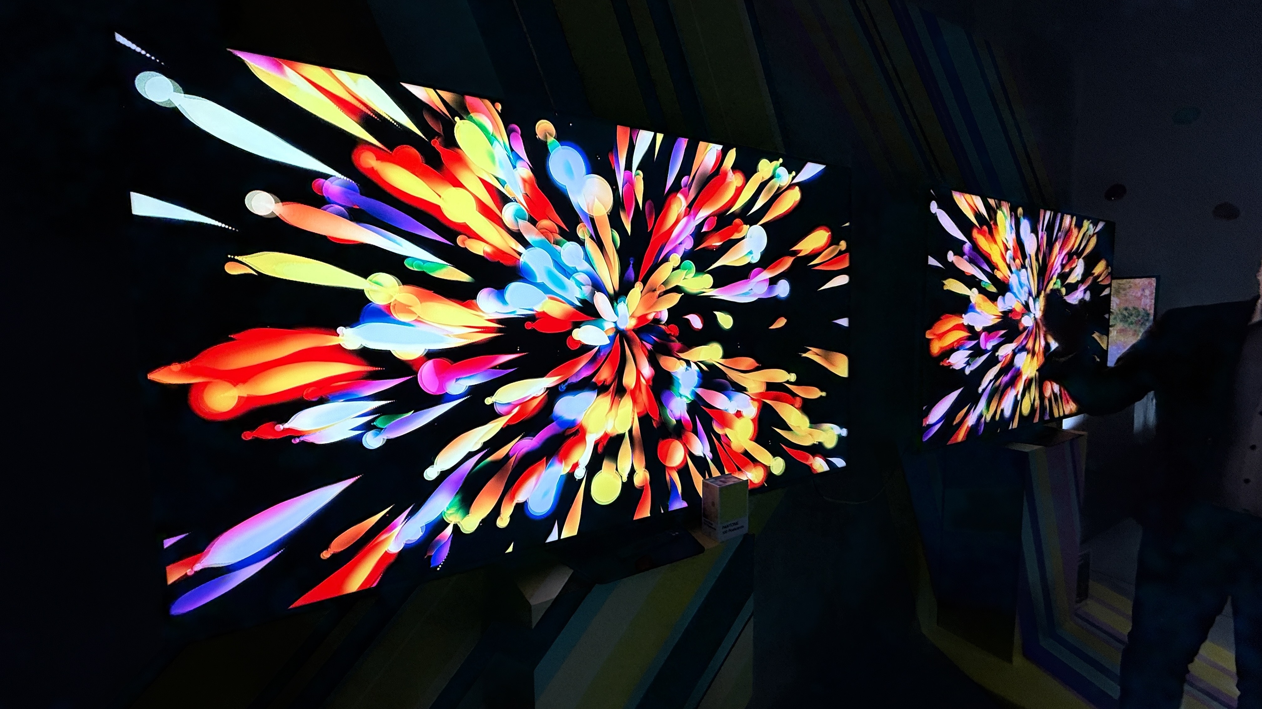 The Hisense UR8S and UR9S RGB TVs are next to each other, with an explosion of colorful streaks on the screen, and deep black tones visible in the background.