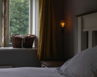 a view from the edge of a bed out of the window where you can see trees