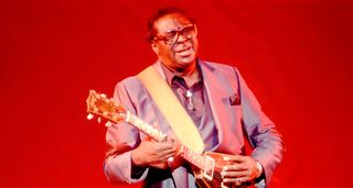 Against a deep red background, Albert King bends a note on his Flying V