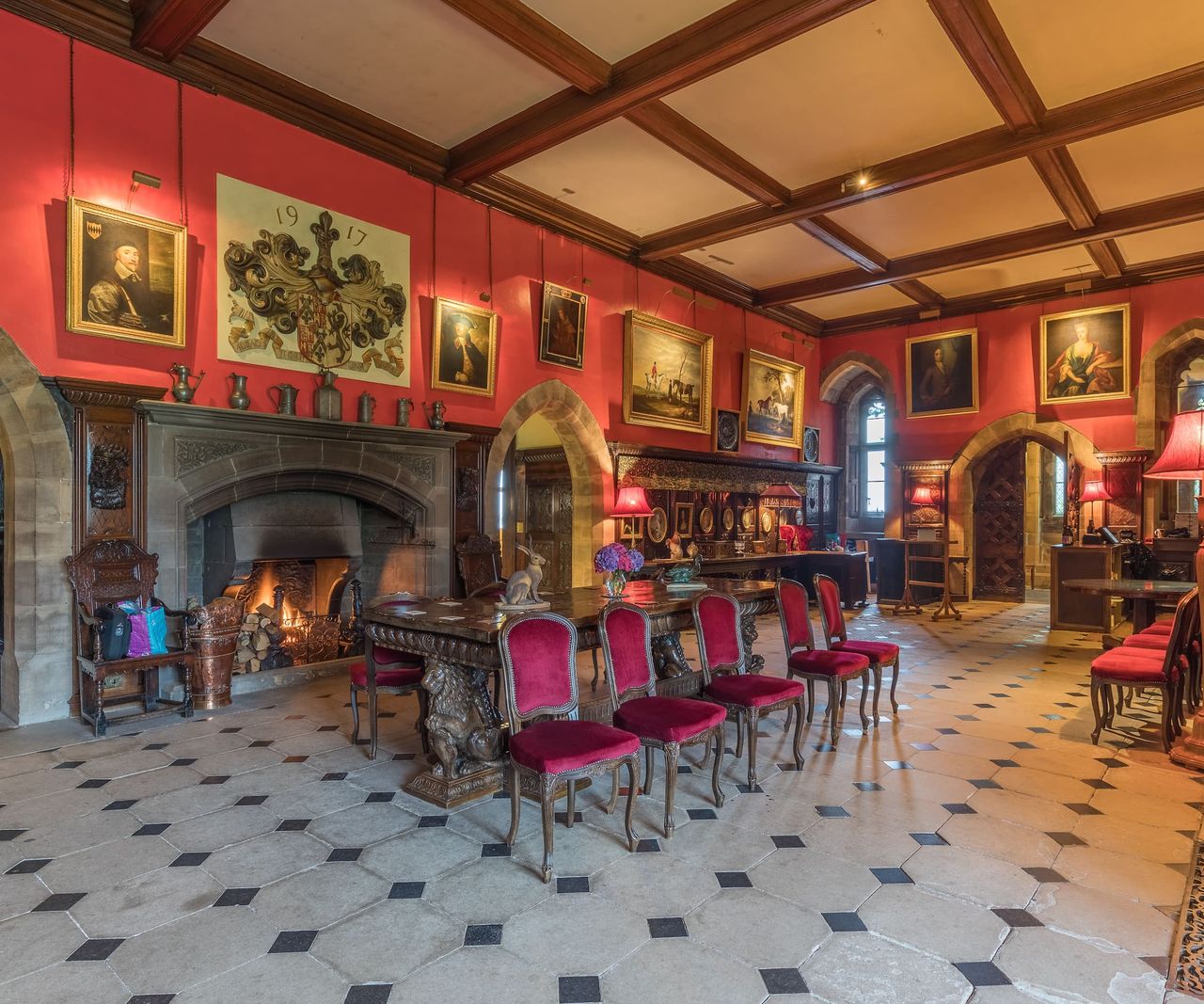 A large dining room with large fireplace with wooden beamed ceiling and square tiled floors