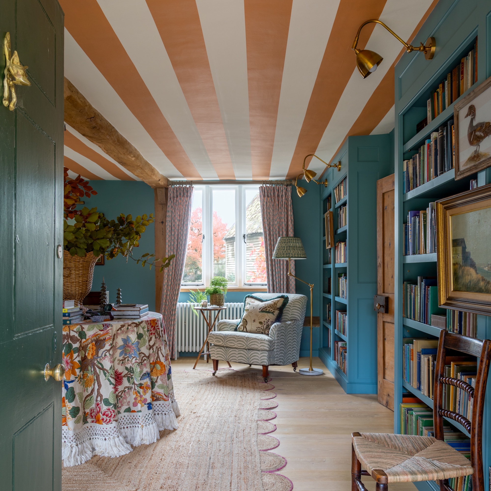 large entrance hall library with ochre and white stripe ceiling, blue bookshelves and table with cloth