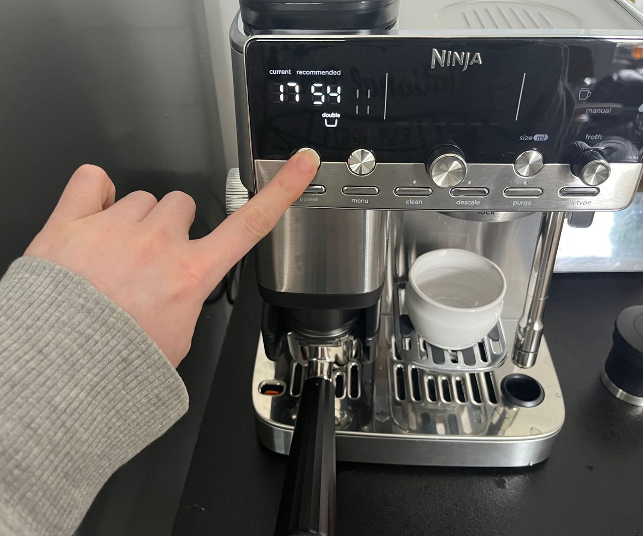 Pressing a button to weight the portafilter on the ninja luxe caf&eacute; mini