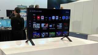 The 27-inch, wireless Displace TV sitting on a display table at a CES 2025 booth. The TV is displaying its smart platform's home screen.