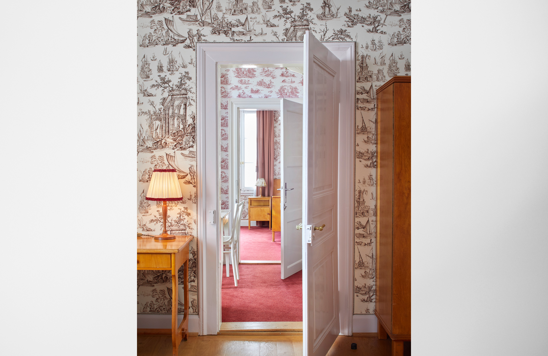 Photo of an open door into rooms wallpapered in floral paper