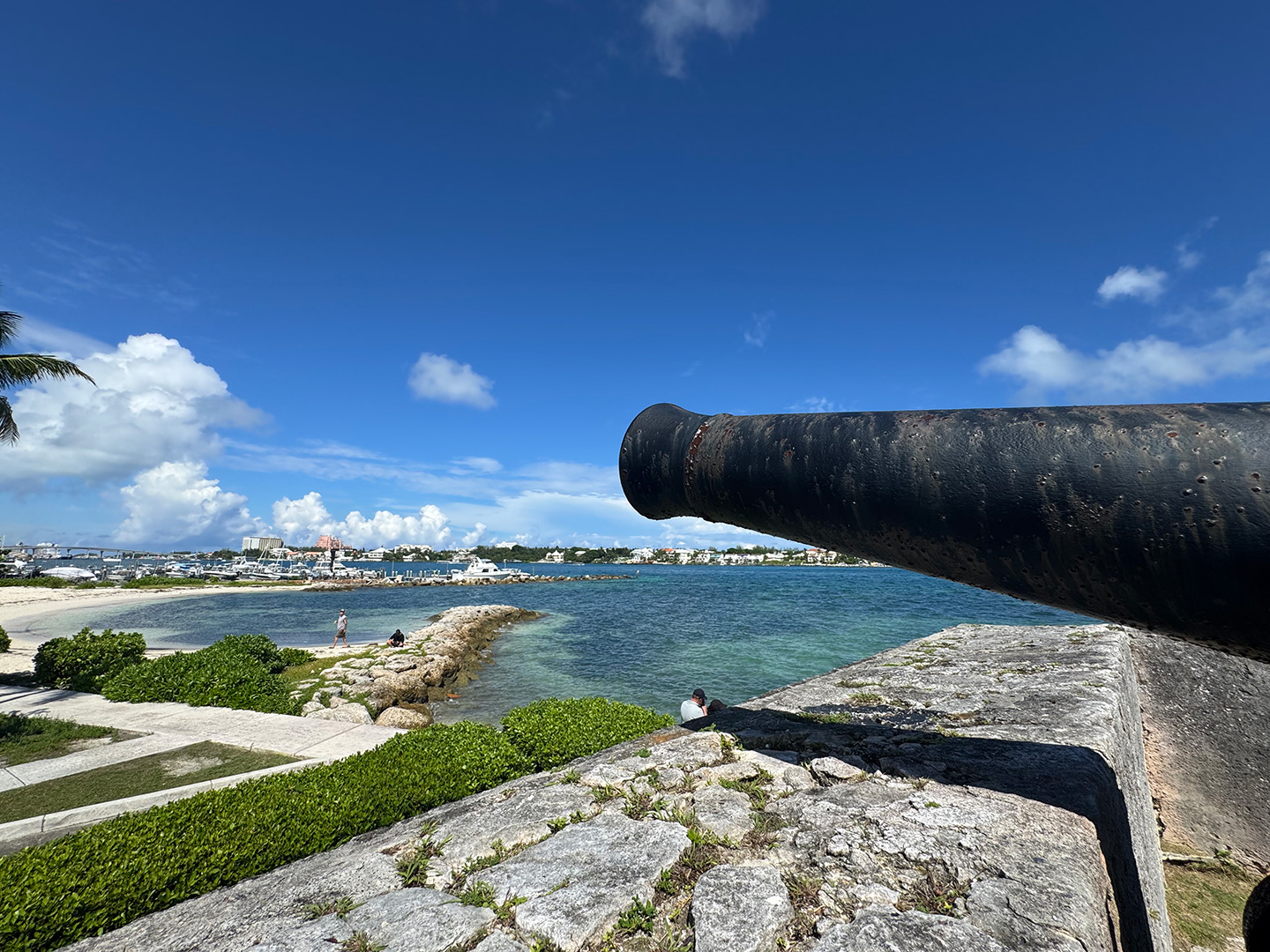 A view of a coastal port harbor with a cannon seen in the foreground.