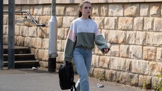 April walking and holding a rucksack