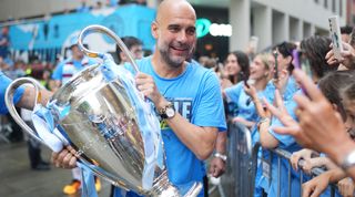Manchester City manager Pep Guardiola carrying the Champions League trophy after the club's treble win in 2023.