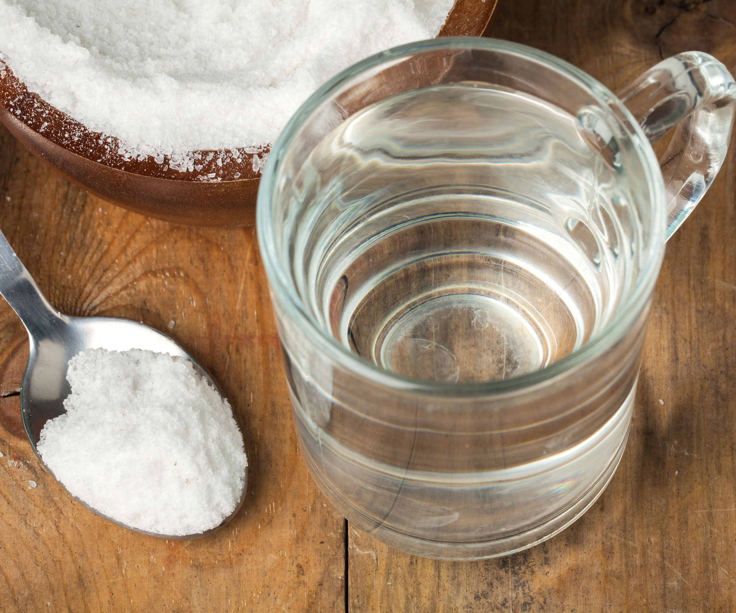 spoon of sugar and glass of water on wooden table