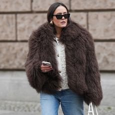 Laura Noltemeyer in Berlin, Germany, wearing a brown fur coat, a white sweater, and light-wash jeans. 