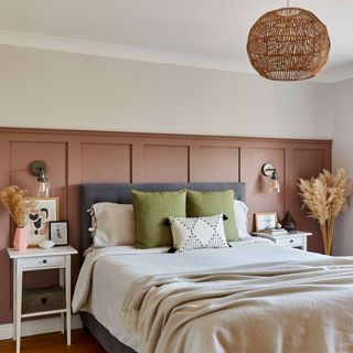 Bedroom with dark pink painted panelling behind bed and green cushions
