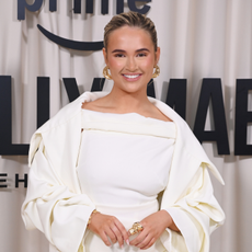 Molly Mae smiling on red carpet wearing white suit.