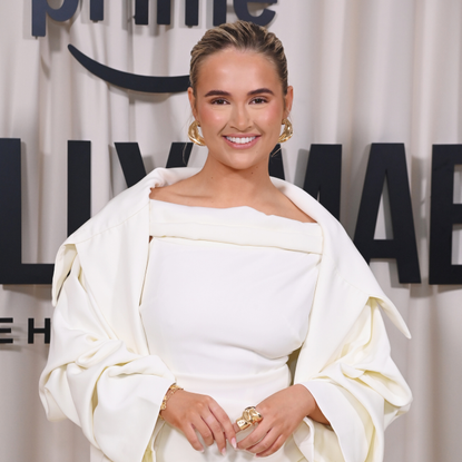 Molly Mae smiling on red carpet wearing white suit.