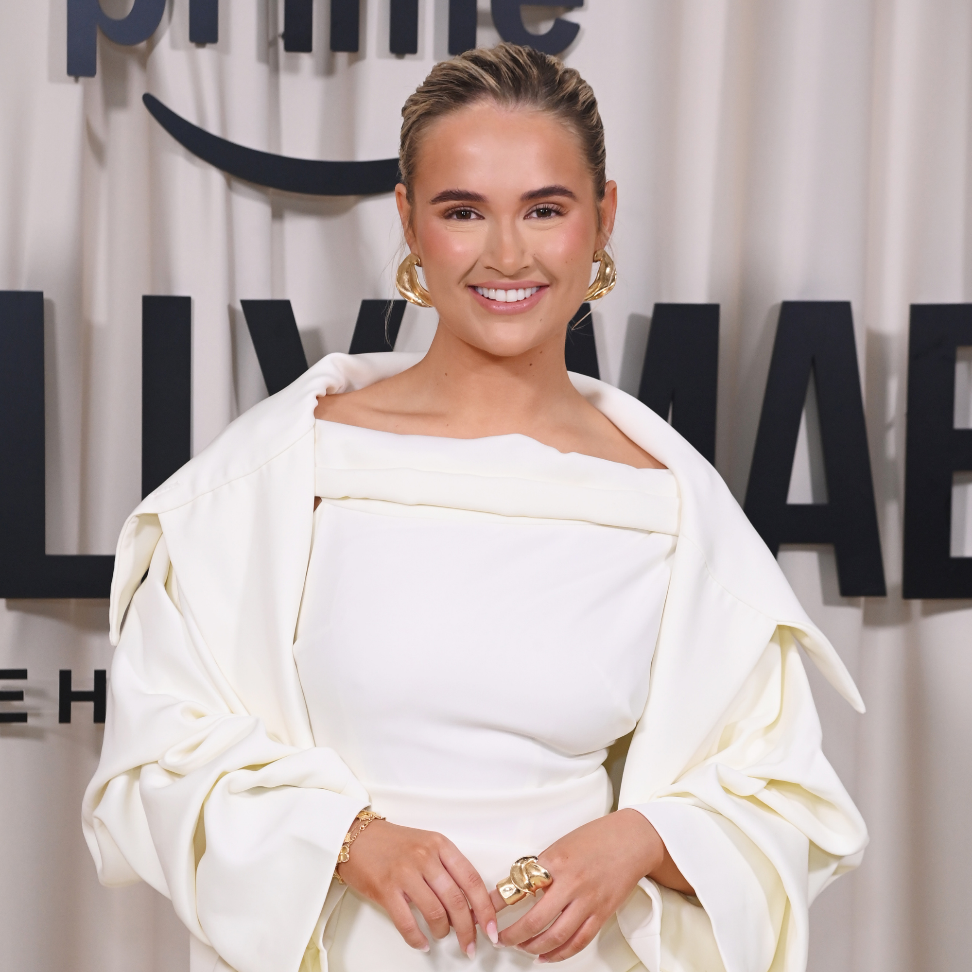 Molly Mae smiling on red carpet wearing white suit.