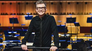 Gareth Malone in a black shirt and tie stands in a conductor's podium in Gareth Malone's Easter Passion