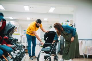 expectant couple shopping looking at a pushchair in a shop