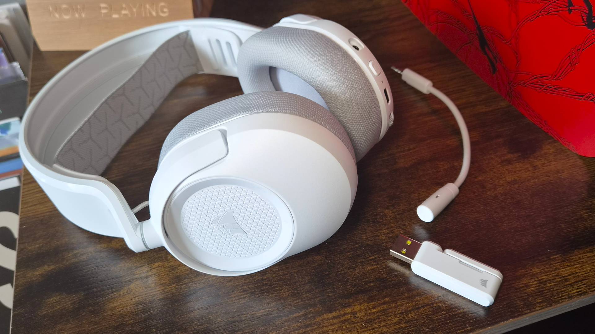 Photo of the Corsair HS35 V3 Wireless headset in white sitting on a wooden cabinet.
