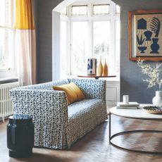 A living room with hardwood floors and a floral-print sofa with a loose cover in a floral print