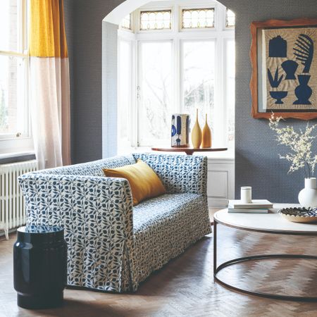 A living room with hardwood floors and a floral-print sofa with a loose cover in a floral print