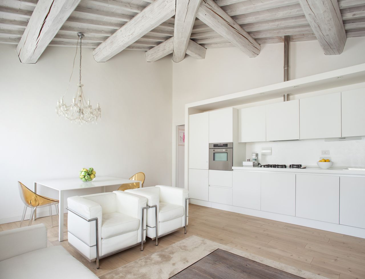 An all-white kitchen with two armchairs and a sofa placed close to it