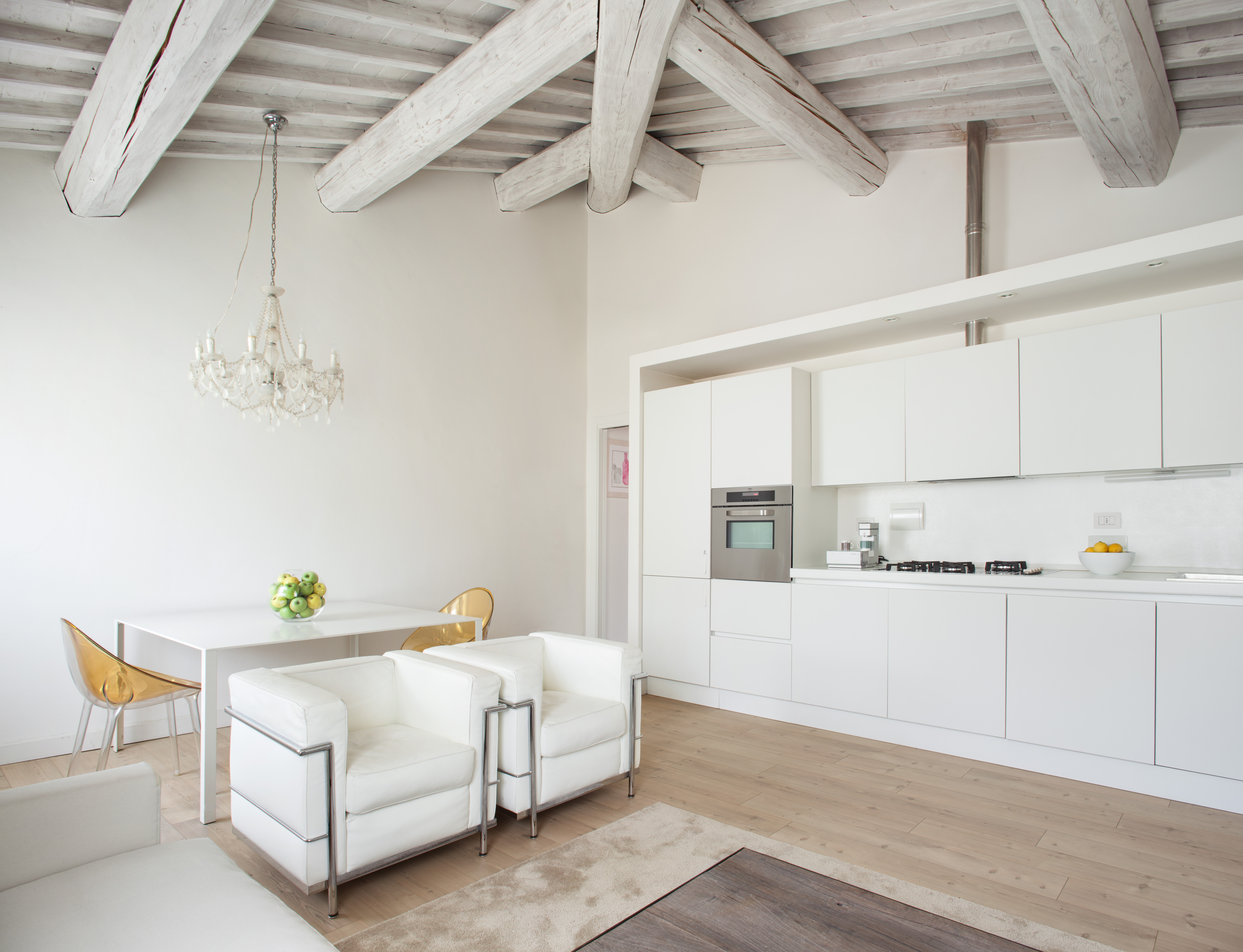 An all-white kitchen with two armchairs and a sofa placed close to it