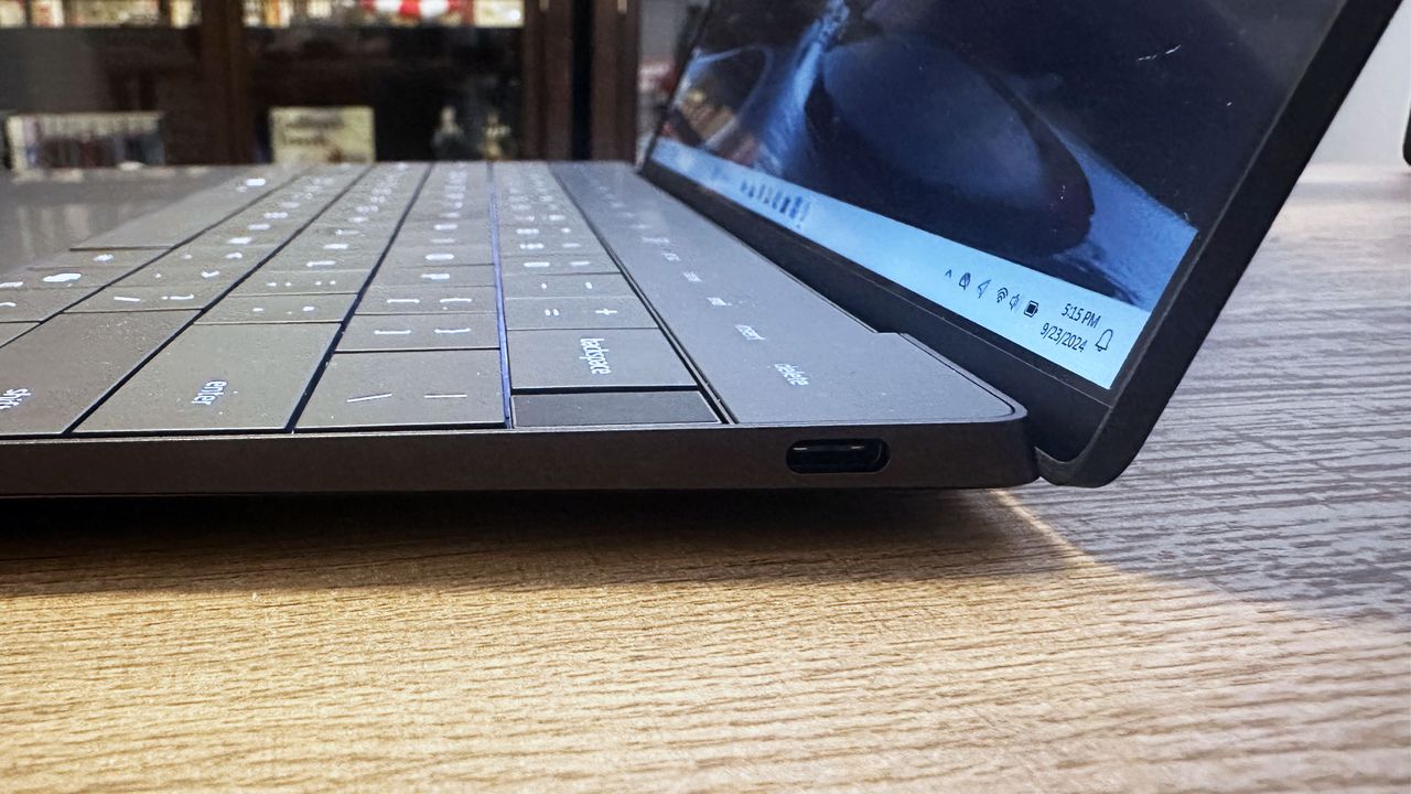 Close up of a USB-C port on a Dell XPS 13 (9350) sitting on a wooden desk.