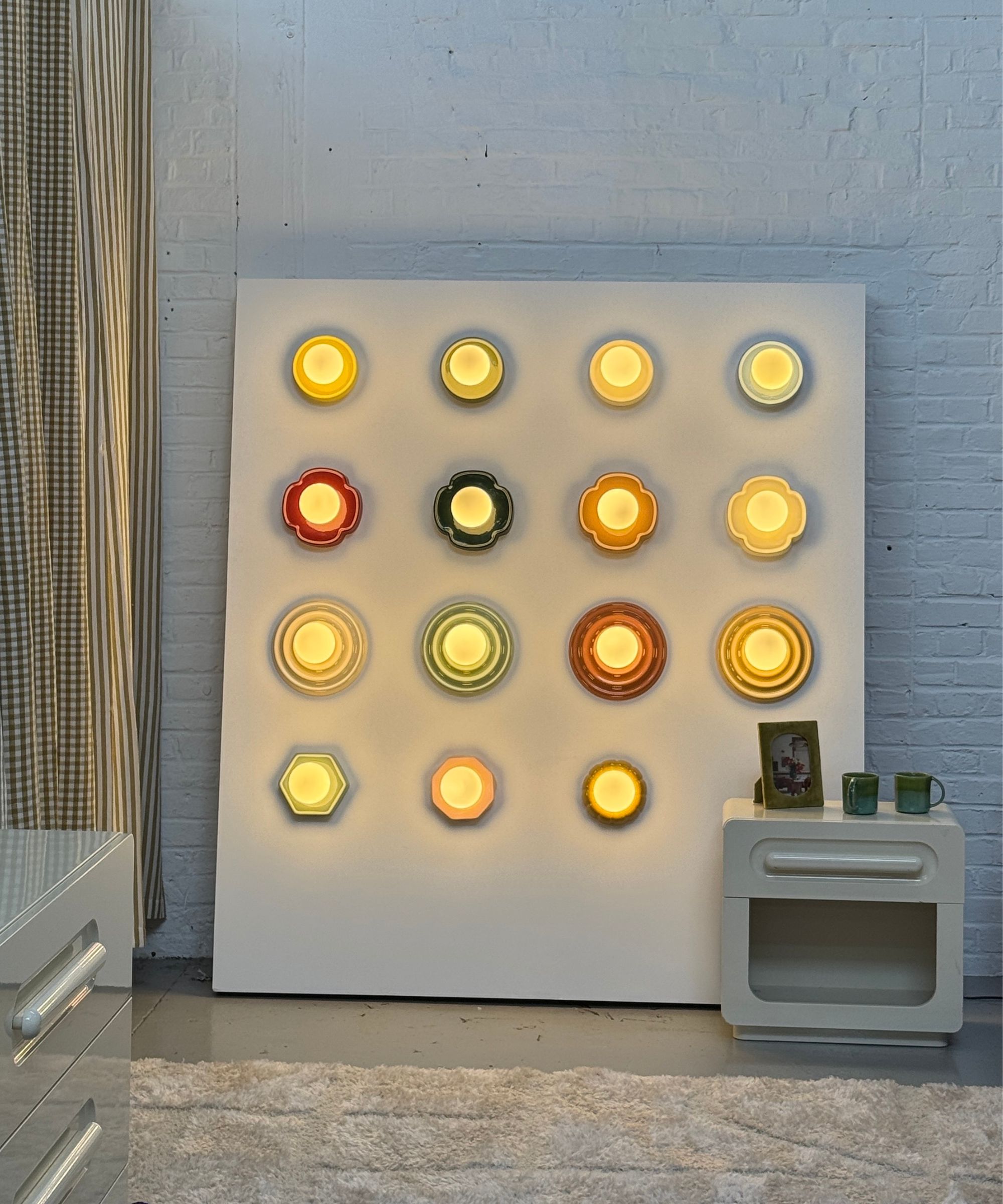 La Redoute wall sconces on a board leaning against a brick wall with a bedside in front