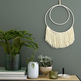 potted plant with fringe wall art and black candle