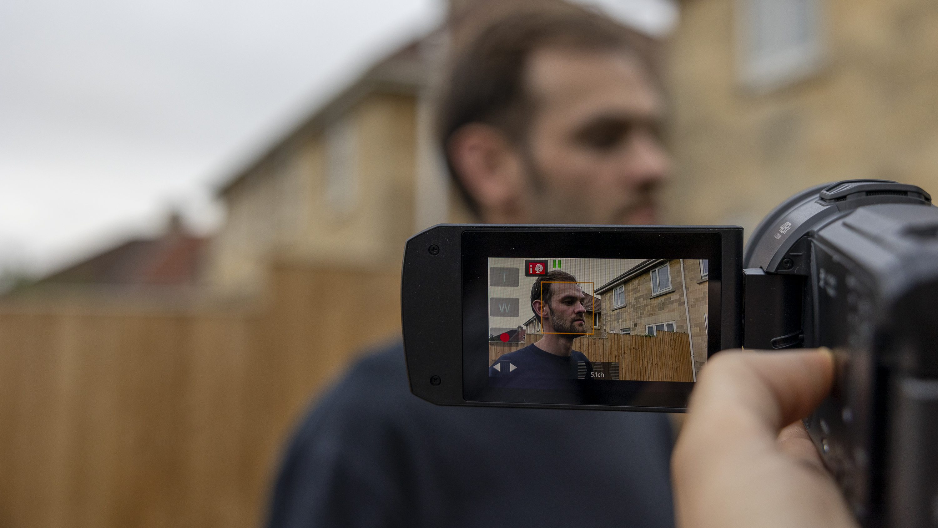 A close-up of the Panasonic HC-V900 LCD screen focusing on a man's face