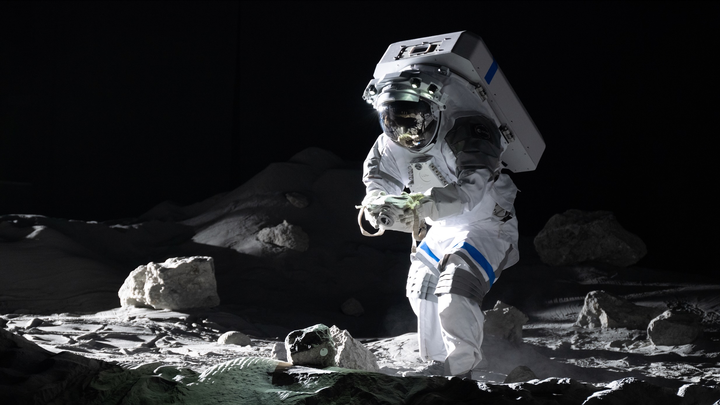 European Space Agency astronaut Matthias Maurer in a simulated moon landscape, taking a picture with a prototype lunar camera.