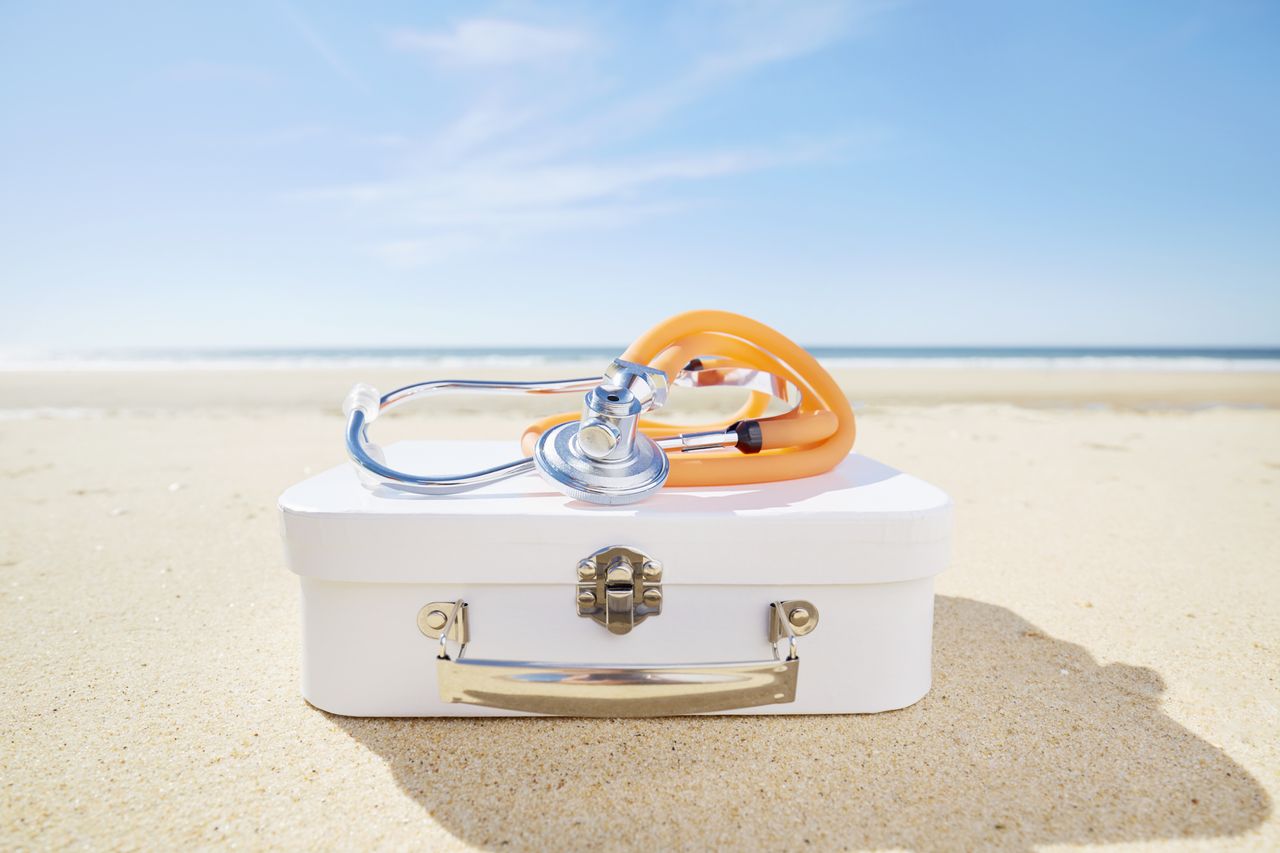 Stethoscope and suitcase on beach by the sea.