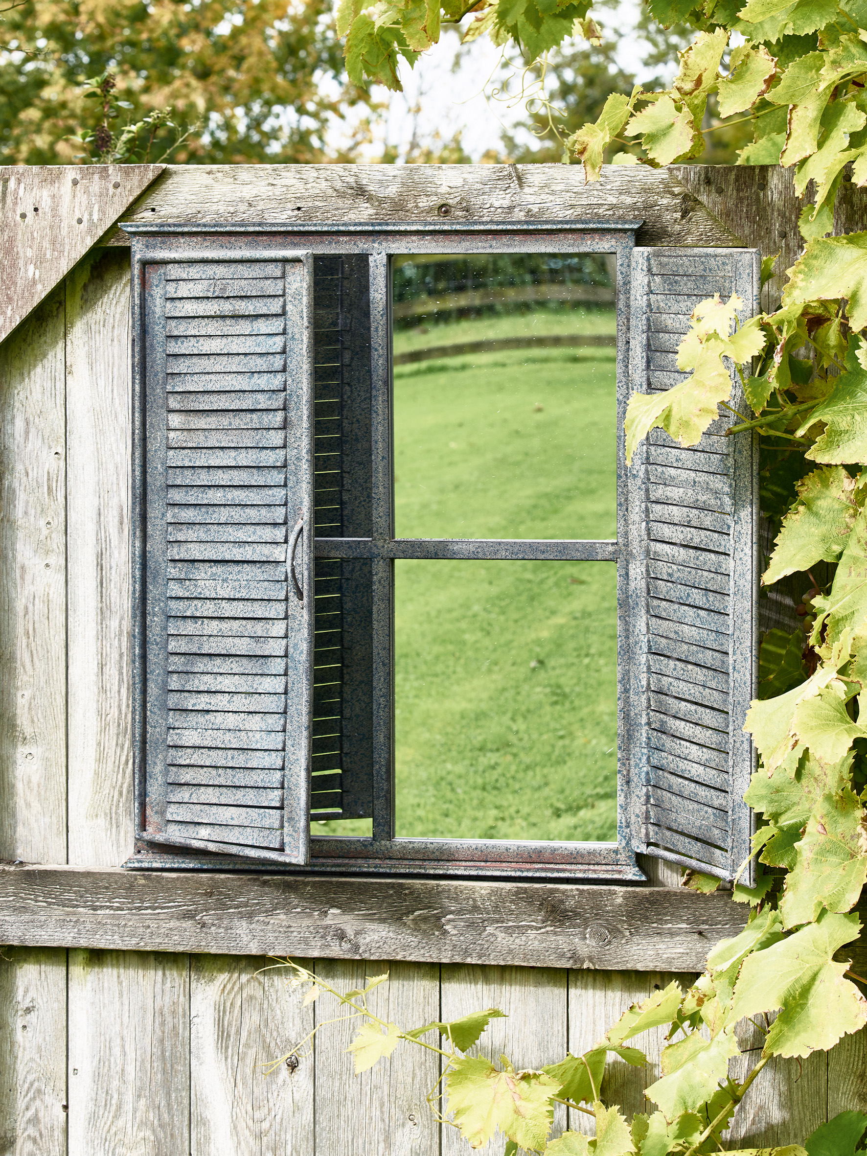 outdoor mirror with shutters on a garden wall