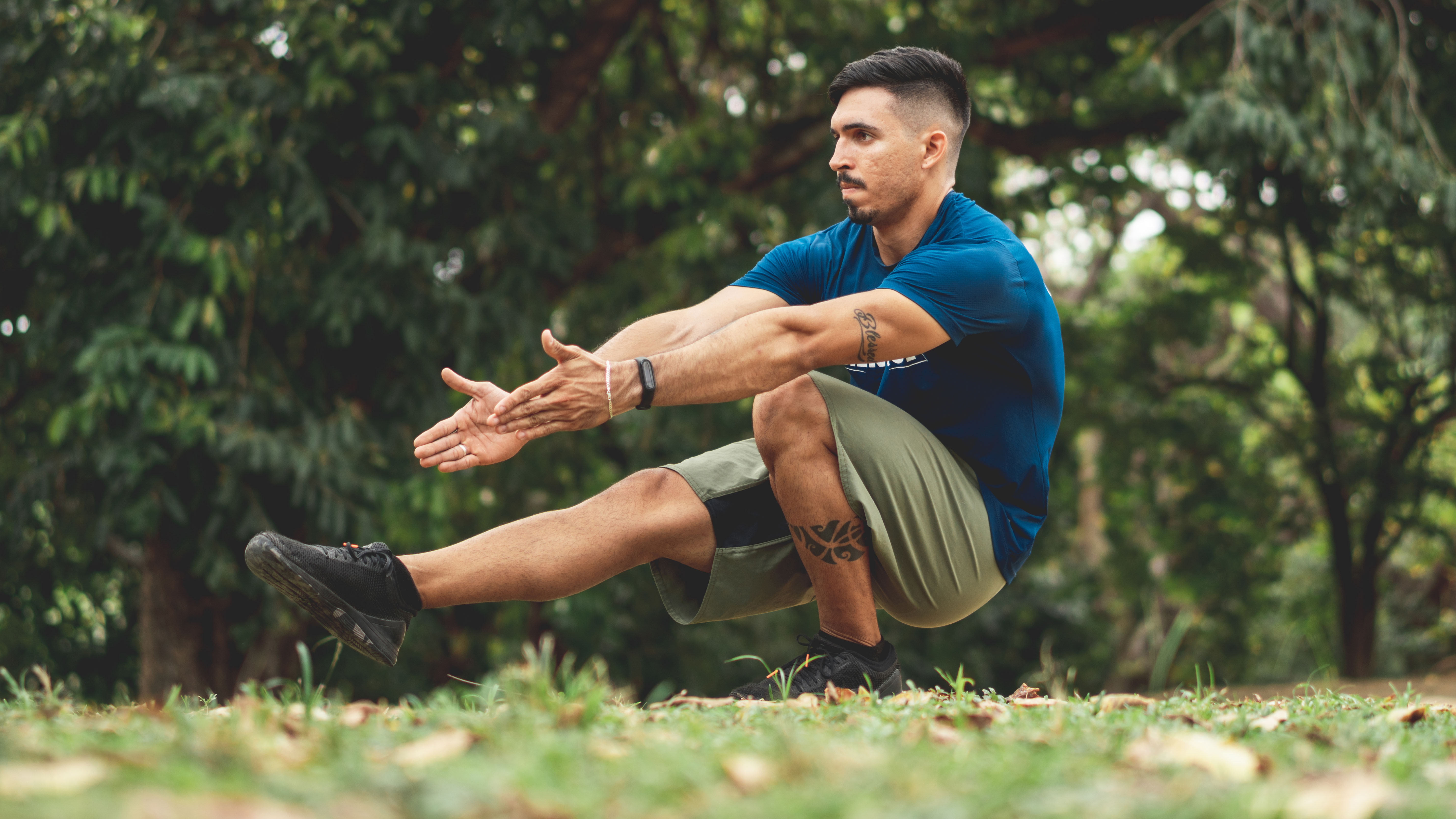 Man performing single leg squat in park