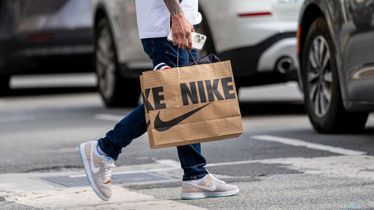 A shopper carries a Nike bag across the street in San Francisco, California.