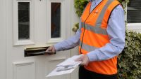 Royal mail postwoman at the front door of a house delivering mail to a customer