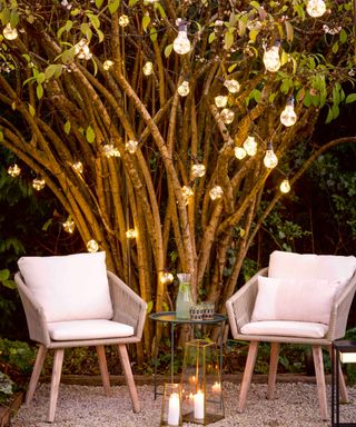 Ambient festoon lighting draped from tree, with floor lanterns, and bistro lounge set.