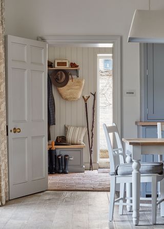 An example of mudroom ideas showing a kitchen with a dining table next to a doorway leading to a mudroom and hallway in one