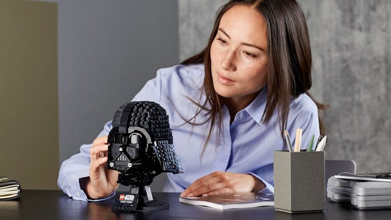 Best Lego Star Wars sets 2022, image shows woman looking at Darth Vader Helmet made from Lego