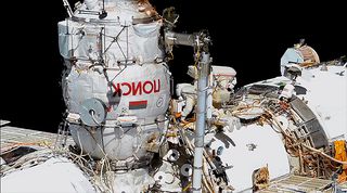 Cosmonauts Sergey Ryzhikov (at top, with red stripes) and Sergey Kud-Sverchkov work outside the Poisk mini-research module during their first spacewalk conducted outside of the International Space Station on Wednesday, Nov. 18, 2020.