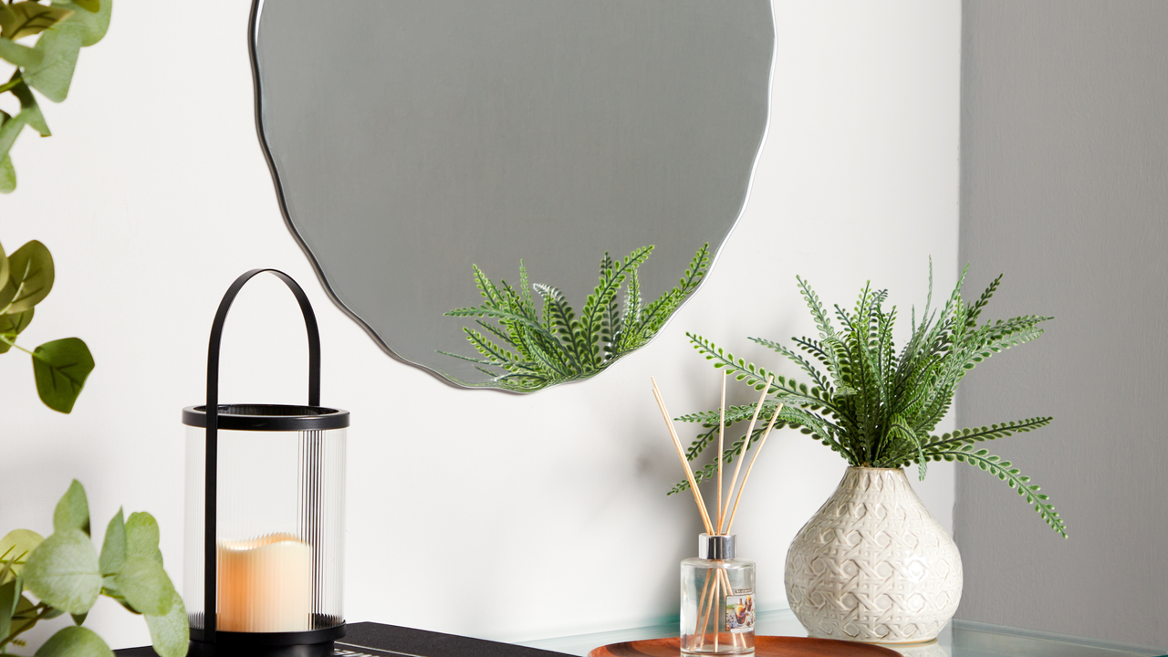 scallop mirror abov shelf with houseplants and candle 