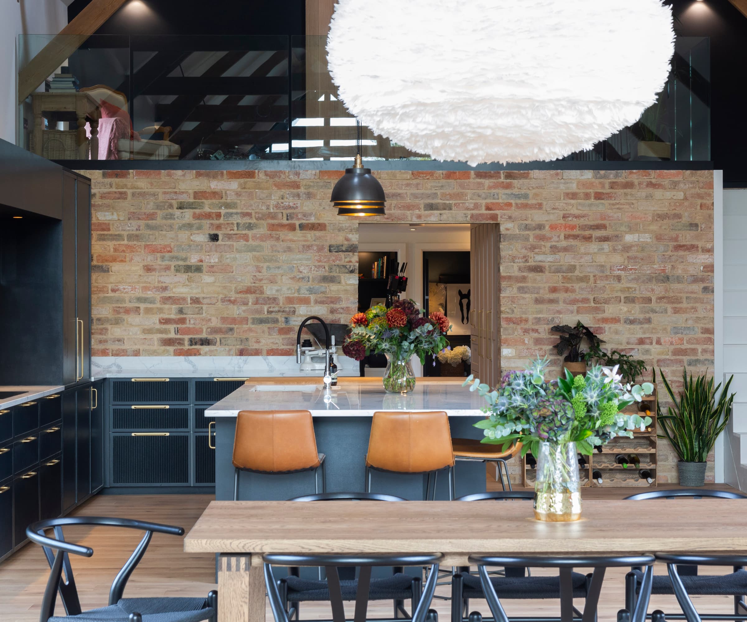 An open plan kitchen with a brick wall inside and a navy blue kitchen and cabinets