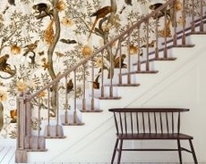White stairs and wood banister with feature wall mural, and bench.