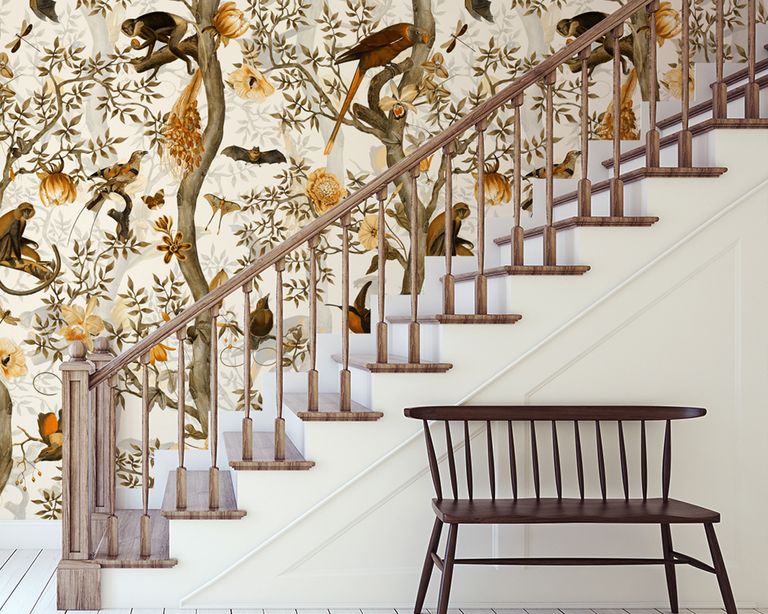 White stairs and wood banister with feature wall mural, and bench.