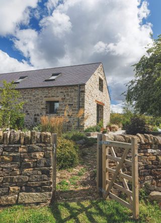 An open gate leading to a contemporary stone barn conversion